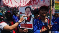 Massa mengenakan pakaian berwarna biru dengan membawa sejumlah atribut organisasi dan alat peraga demo.