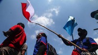 Massa aksi berbaris membawa beberapa spanduk protes. Mereka juga terlihat membawa bendera merah putih.