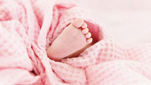 Tiny little cute baby foot under pink blanket.