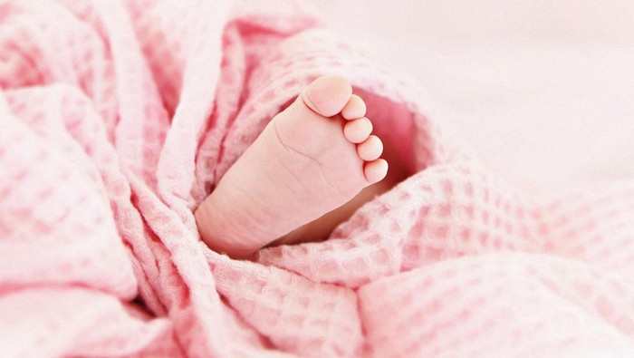 Tiny little cute baby foot under pink blanket.