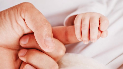 Paternity. Newborn and parent. Tiny newborn hand holding fathers finger, soft color tone. Parenting, childcare and healthcare concept. Family and home concept. Health care, pediatrics.