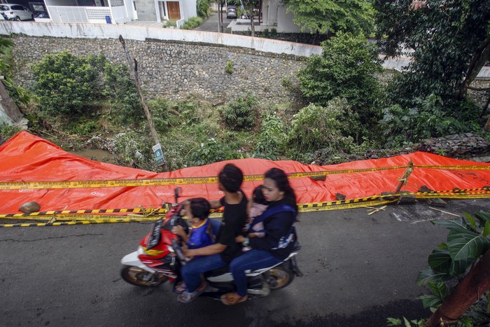 Pengendara sepeda motor melintas di dekat jalan alternatif Cilebut yang longsor di Bogor, Jawa Barat, Senin (12/9/2022). Jalan alternatif penghubung Kota Bogor dan Kabupaten Bogor itu longsor dan menghancurkan separuh jalan yang diakibatkan oleh tingginya curah hujan pada Minggu (11/9/2022). ANTARA FOTO/Yulius Satria Wijaya/aww.