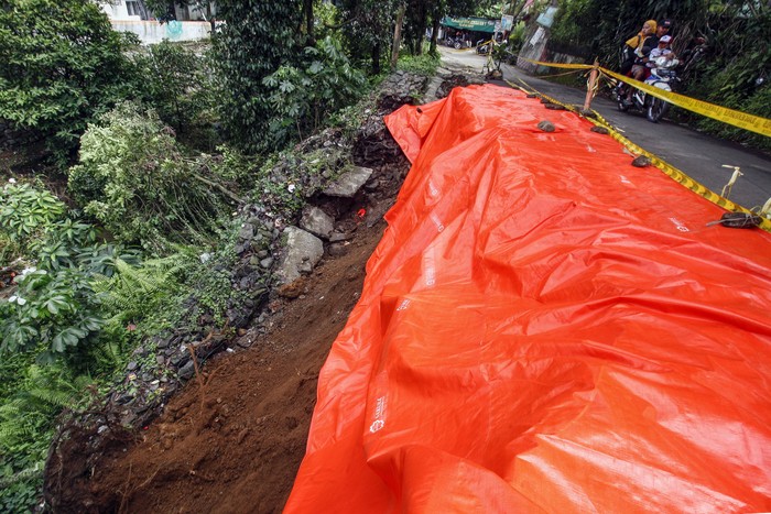 JALAN LONGSOR DI BOGOR Pengendara sepeda motor melintas di dekat jalan alternatif Cilebut yang longsor di Bogor, Jawa Barat, Senin (12/9/2022). Jalan alternatif penghubung Kota Bogor dan Kabupaten Bogor itu longsor dan menghancurkan separuh jalan yang diakibatkan oleh tingginya curah hujan pada Minggu (11/9/2022). ANTARA FOTO/Yulius Satria Wijaya/aww.