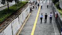 Pejalan kaki melintasi jalur pedestrian yang diacak-acak proyek galian kabel. 