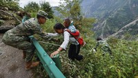 Petugas membantu warga ke luar dari semak-semak. Dilaporkan 83 orang tewas akibat guncangan gempa ini. (AP Photo/Shen Bohan)  