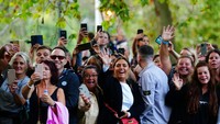 Para pendukung antusias menyambut Raja Charles III. Mereka merekam dengan handphone momen saat Raja Charles III melintas. (AP/Victoria Jones)