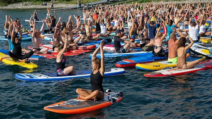 11 September 2022, Baden-Wuerttemberg, Überlingen: During a yoga class on Lake Constance, participants complete their exercise on stand-up paddles (SUPs). With 305 participants, they set a new world record. Photo: Stefan Puchner/dpa (Photo by Stefan Puchner/picture alliance via Getty Images)