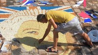 Seniman Kosovo, Alken Pozhega membuat potret wajah Ratu Elizabeth II di pinggir jalan kota Gjakova, Kosovo, Sabtu (10/9/2022).