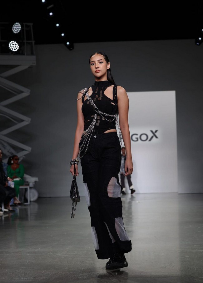 Anya Geraldine tampil bak model profesional dengan atasan halter berdetail cut-out yang dipadukan rok panjang berdetail mesh transparan. Rantai metal yang melilit tubuhnya menambah kesan edgy pada penampilan. Foto: Instagram/@erigostore