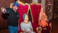 Pengunjung berselfie dengan patung Ratu Elizabeth II yang sedang duduk di kursi kerajaan.