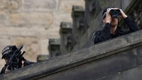 Anggota keamanan memantau situasi saat peti mati Ratu Elizabeth II akan melakukan perjalanan menuju tempat persemayaman. Jutaan orang diprediksi akan berbondong-bondong ke London saat pemakaman Ratu Elizabeth II, untuk itu keamanan ketat diperlukan. (Odd Andersen/AFP/Getty Images)