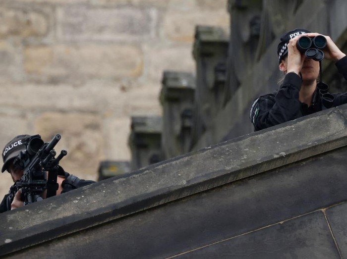 Police officers with snipers stand on the roof of St Giles Cathedral in Edinburgh on September 11, 2022, where Queen Elizabeth II will lie at rest. - Queen Elizabeth IIs coffin will travel by road through Scottish towns and villages on Sunday as it begins its final journey from her beloved Scottish retreat of Balmoral. The Queen, who died on September 8, will be taken to the Palace of Holyroodhouse before lying at rest in St Giles Cathedral, before travelling onwards to London for her funeral. (Photo by Odd ANDERSEN / AFP) (Photo by ODD ANDERSEN/AFP via Getty Images)