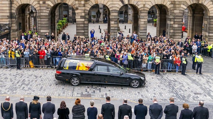 The hearse carrying the coffin of Queen Elizabeth II, draped with the Royal Standard of Scotland, passes the City Chambers on the Royal Mile, Edinburgh, Sunday, Sept. 11, 2022 on the journey from Balmoral to the Palace of Holyroodhouse in Edinburgh, where it will lie in rest for a day. (Jane Barlow/Pool Photo via AP)