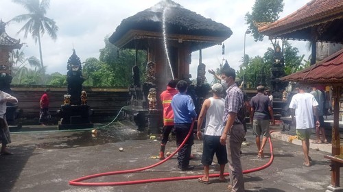 Proses pemadaman api pada atap Gedong Dalem di Pura Dalem Banjar Adat Meliling, Kecamatan Kerambitan, yang terbakar pada Selasa (13/9/2022) siang.