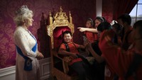 Seorang siswa, duduk di mock-up kursi kerajaan, melihat patung lilin Ratu Elizabeth II Inggris di Museum Madame Tussauds di Beijing, Cina, 19 September 2014. (AP/Andy Wong)
