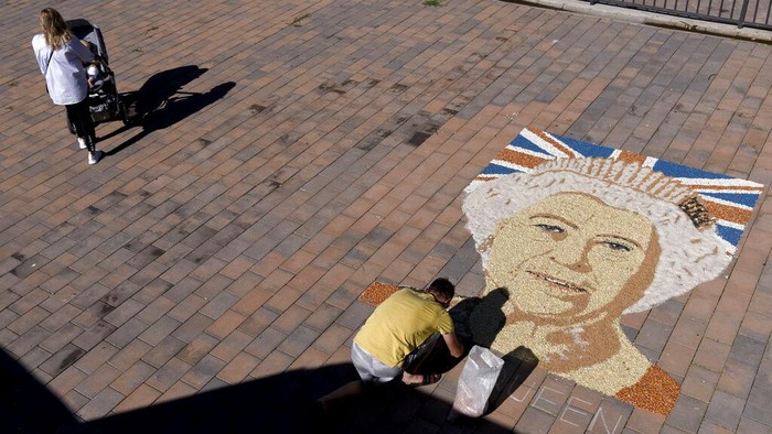 Artist Alken Pozhega makes a giant portrait of Britain's Queen Elizabeth II, made entirely of grain of corn, peas and beans in the town of Gjakova, Kosovo, Sept. 10, 2022. (AP Photo/Sylejman Kllokoqi)