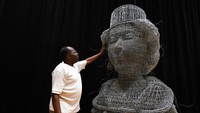 Artis Carl Gabriel menyentuh patungnya yang terbuat dari kawat yang menggambarkan kepala Ratu Elizabeth II di London, 1 Juni 2022. Patung dibuat untuk Kontes Jubilee, menjelang akhir pekan Platinum Jubilee.  (AP/Alberto Pezzali)