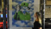 Seorang warga berjalan melewati poster Ratu Elizabeth.
