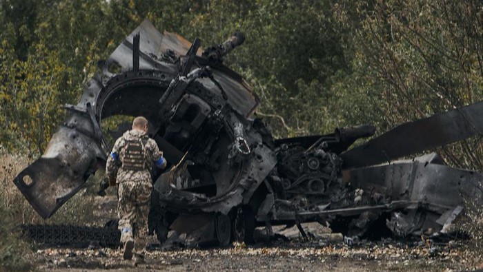 A Ukrainian soldier passes by a Russian tank damaged in a battle in a just freed territory on the road to Balakleya in the Kharkiv region, Ukraine, Sunday, Sept. 11, 2022. (AP Photo)