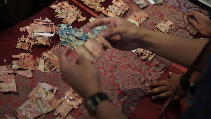Petugas Bank Indonesia Solo memeriksa uang rusak milik Samin akibat dimakan rayap di Kantor Bank Indonesia, Solo, Jawa Tengah, Selasa (13/9/2022). Seorang warga Solo, Samin (53 tahun), yang bekerja sebagai penjaga sekolah mengalami kerugian sekitar 50 juta karena uang tabungan haji miliknya rusak dimakan rayap akibat menyimpan di celengan plastik rumah. ANTARA FOTO/Mohammad Ayudha/aww.