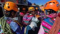 Para erempuan adat Aymara yang tergabung dalam Climbing Cholitas of Bolivia Warmis mengenakan helm mereka dan menyiapkan perlengkapan pendakian mereka saat menunggu bus untuk pendakiannya, di El Alto, Bolivia, Sabtu, (13/9/2022).