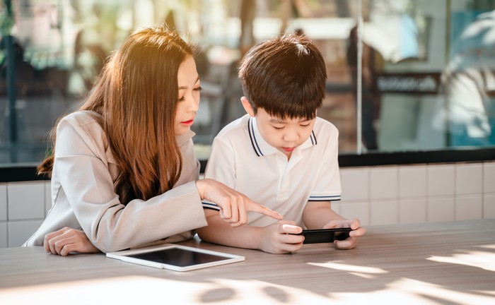 Business woman working online in cafe with kid. Asian family lifestyle with mobile phone and digital tablet.
