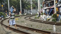 Warga menggotong air mineral galonan melintasi rel kereta api di Benhil, Jakarta. 