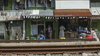 Warga beraktivitas di samping rel kereta yang padat penduduk.
