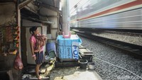 Warga menggendong bayi di saat bunyi kereta yang sangat keras melintas. 