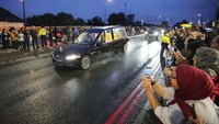 Warga memadari jalan yang dilintasi iring-iringan mobil jenazah Ratu Elizabeth II. (AP Photo/Martin Meissner).