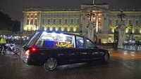 Mobil jenazah menggunakan penerangan di dalamnya, memperlihatkan peti mati yang membawa jenazah Ratu Elizabeth II tiba di Istana Buckingham. Keesokannya, jenazah Ratu Elizabeth akan dibawa ke Westminster Hall untuk disemayamkan selama beberapa hari hingga upacara pemakaman kenegaraan di Westminster Abbey pada 19 September. Jenazah Ratu Elizabeth kemudian dimakamkan ke Kapel St George di Kastil Windsor. (Gareth Fuller/Pool Photo via AP).
