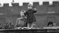 Foto saat Ratu Elizabeth dan Pangeran Charles di balik dinding Clarence House, London saat menyaksikan prosesi kunjungan Ratu Juliana dari Belanda, 22 November 1950. (Fox Photos/Hulton Archive/Getty Images)