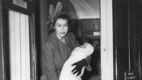 Foto saat Ratu Elizabeth II menaiki gerbong kereta api kelas satu, saat melakukan perjalanan ke Kastil Balmoral, Skotlandia. Ia terlihat menggendong Putri Anne, sementara Pangeran Charles berdiri di sampingnya. (Reg Speller/Fox Photos/Hulton Archive/Getty Images)