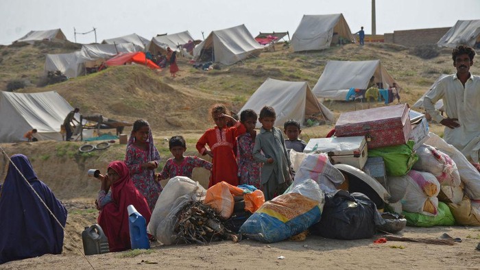 Korban Banjir Pakistan Antre Panjang Demi Makanan TOPSHOT - Displaced flood-affected people stand in a queue to receive food being distributed by Saylani Welfare Trust at a makeshift camp in flood-hit Sehwan of Sindh province on September 13, 2022. (Photo by Husnain ALI / AFP) (Photo by HUSNAIN ALI/AFP via Getty Images)