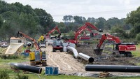 Para pekerja mulai mengeruk tanah dengan truk untuk membangun terminal LNG di Wilhelmshaven, Jerman. Lokasi terminal LNG ini tak jauh dari pelabuhan Laut Utara.
