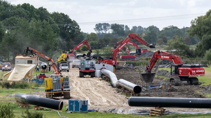 Pembangunan pipa gas alam LNG WILHELMSHAVEN, GERMANY - SEPTEMBER 13: In this aerial view workers construct a pipeline for transporting natural gas from the new, nearby liquified natural gas (LNG) terminal to the Etzel underground storage facility on September 13, 2022 near Wilhelmshaven, Germany. The new terminal will allow the docking of floating storage and regasification units (FSRU), which are ships that can convert liquified natural gas back into gas form and then deliver it directly into Germany's gas network and storage system. Natural gas from the Wilhelmshaven terminal will be sent through a 30km pipeline to the Etzel underground storage facility. The new terminal, scheduled for completion by the end of this year, will allow Germany to import LNG by ship from countries including the USA and Qatar in order to lower Germany's reliance on gas imports from Russia. (Photo by David Hecker/Getty Images)