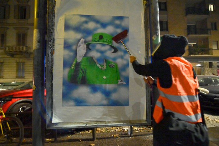 Seniman Bertopeng Buat Potret Ratu Elizabeth II Ada di Atas Langit TURIN, ITALY - SEPTEMBER 12: The street artist Andrea Villa arranges a poster created by him commemorating Queen Elizabeth II Death on September 12, 2022 in Turin, Italy. Queen Elizabeth II died at Balmoral Castle in Scotland on September 8, 2022, and is succeeded by her eldest son, King Charles III. (Photo by Stefano Guidi/Getty Images)