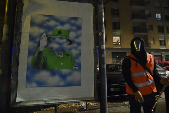 Seniman Bertopeng Buat Potret Ratu Elizabeth II Ada di Atas Langit TURIN, ITALY - SEPTEMBER 12: The street artist Andrea Villa arranges a poster created by him commemorating Queen Elizabeth II Death on September 12, 2022 in Turin, Italy. Queen Elizabeth II died at Balmoral Castle in Scotland on September 8, 2022, and is succeeded by her eldest son, King Charles III. (Photo by Stefano Guidi/Getty Images)