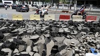 Pengendara melintas di samping jalan yang sedang dalam proyek perbaikan jalur pedestrian. Panjang aspal jalan yang dibongkar kurang lebih 50 meter.