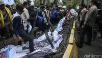 Massa tampak merobohkan kawat berduri yang dipasang polisi.