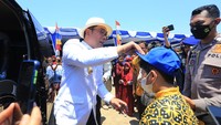Gubernur Jawa Barat Ridwan Kamil membetulkan letak topi seorang pelajar saat bakti sosial di kampung nelayan Karangsong, Indramayu, Jawa Barat, Kamis (15/9/2022).