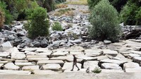 Seorang pria berjalan di dasar Sungai Sangone, anak sungai Po, saat wilayah tersebut mengalami kekeringan terburuk dalam 70 tahun, di Beinasco, Turin, Italia, 19 Juni. (Massimo Pinca/Reuters).