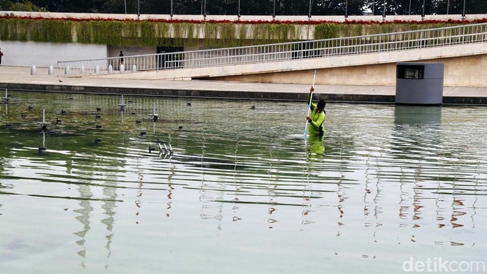 Petugas melakukan perawatan kolam air mancur di Lapangan Banteng, Jakarta. Petugas tampak nyebur ke kolam.