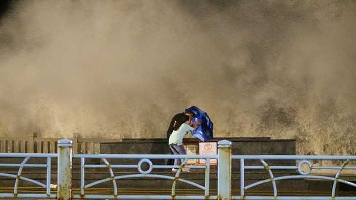 China Siaga Terjangan Topan Muifa LIANYUNGANG, CHINA - SEPTEMBER 14: People hold umbrellas to avoid high waves as Typhoon Muifa approaches on September 14, 2022 in Lianyungang, Jiangsu Province of China. Muifa, the 12th typhoon this year, is expected to make landfall in the coastal areas of the northern part of southeast China's Zhejiang Province on Wednesday night. (Photo by VCG/VCG via Getty Images)