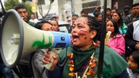 Seorang wanita bersuara menggunakan pengeras suara saat berdemo di depan Mahkamah Konstitusi Quito, Selasa (6/9/2022). Mereka menuntut keputusan untuk menghentikan penambangan dan ekstraksi minyak di wilayah mereka. (Rodrigo Buendia/Getty Images)