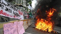 Mahasiswa berusaha memanjat pagar berduri dekat Istana Kepresidenan, Jakarta Pusat, Selasa (13/9/2022). Terlihat poster yang bertuliskan tolak kenaikan BBM dan api yang berkobar serta asap yang tebal memenuhi kawasan teersebut. (Eko Siswono/Getty Images)