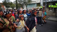 Masyarakat adat Waorani dan Cofan melakukan aksi demo di depan Mahkamah Konstitusi (MK) Quito, Selasa (6/9/2022). Terlihat sejumlah polisi berjaga di depan MK. (Rodrigo Buendia/Getty Images)