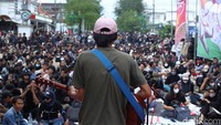 Massa aksi yang terdiri dari berbagai elemen mahasiswa menggelar aksi damai di kawasan Jalan Malioboro, Jogja. Seorang mahasiswa membawakan lagu dengan memainkan gitar di panggung rakyat. Foto: Pius Erlangga/detikJateng
