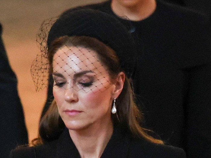 Gaya Berkabung Kate Middleton dan Meghan Markle LONDON, ENGLAND - SEPTEMBER 14: Britains Catherine, Princess of Wales and Meghan, Duchess of Sussex walk as procession with the coffin of Britains Queen Elizabeth arrives at Westminster Hall from Buckingham Palace for her lying in state, on September 14, 2022 in London, England. (Phil Noble - WPA Pool/Getty Images)