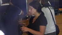 Sali Hafez (tengah), melihat teleponnya setelah membobol cabang Bank BLOM di Beirut, Lebanon, Rabu, (14/9/2022) dengan mengacungkan pistol mainan dan mengambil $13.000 dari rekening tabungannya.  Dia mengatakan dia telah berulang kali mengunjungi bank untuk meminta uangnya dan diberitahu bahwa dia hanya bisa menerima $200 sebulan dalam pound Lebanon. Hafez mengatakan pistol mainan itu milik keponakannya.